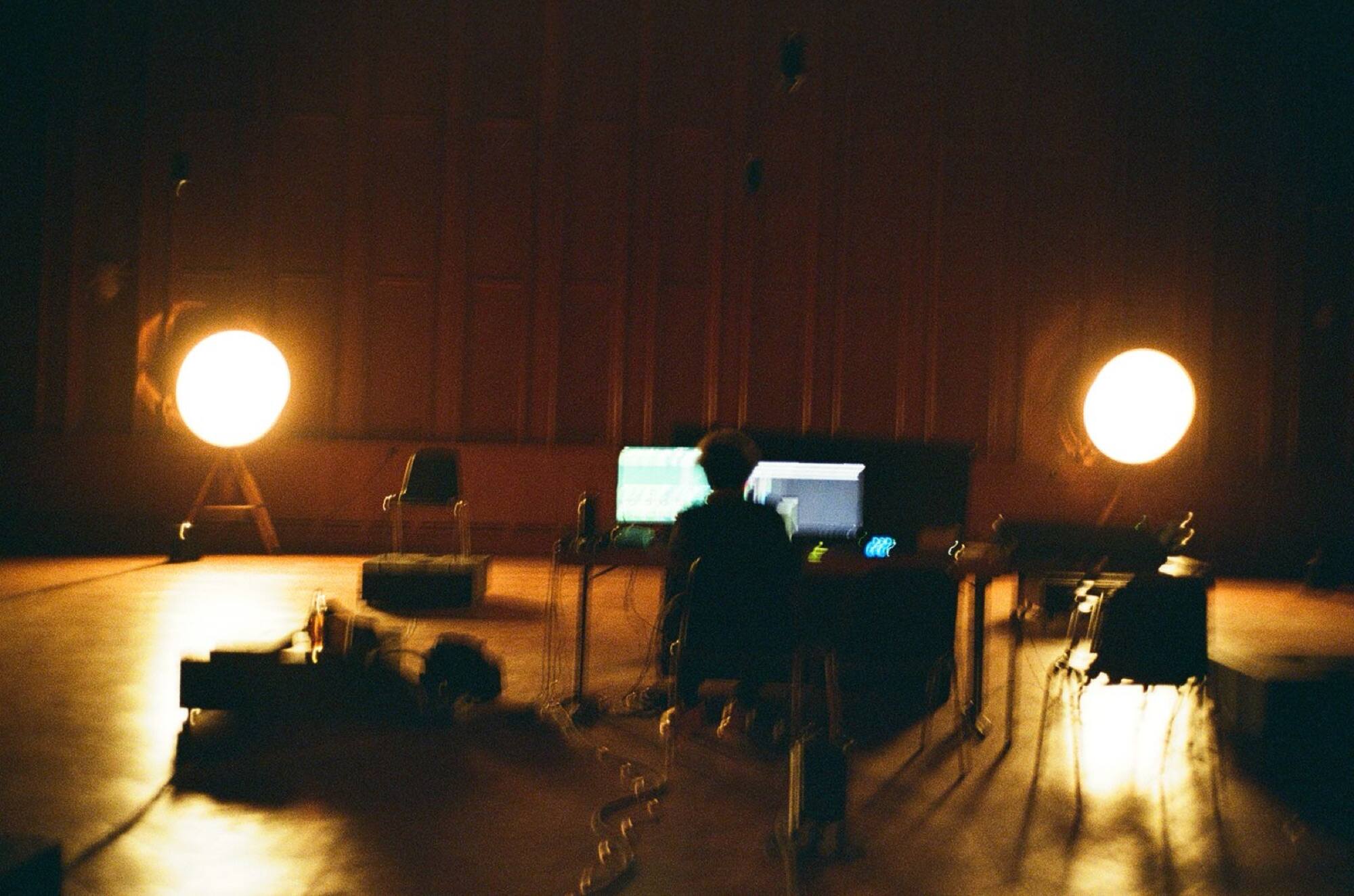 Henrique Matias performing in near darkness between two glowing spherical lamps